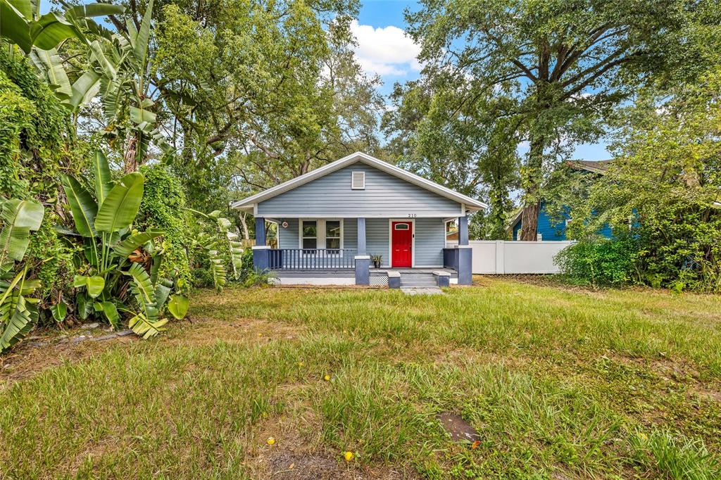 A light blue bungalow with a red front door and a covered front porch — 210 E CLUSTER AVENUE, TAMPA, FL