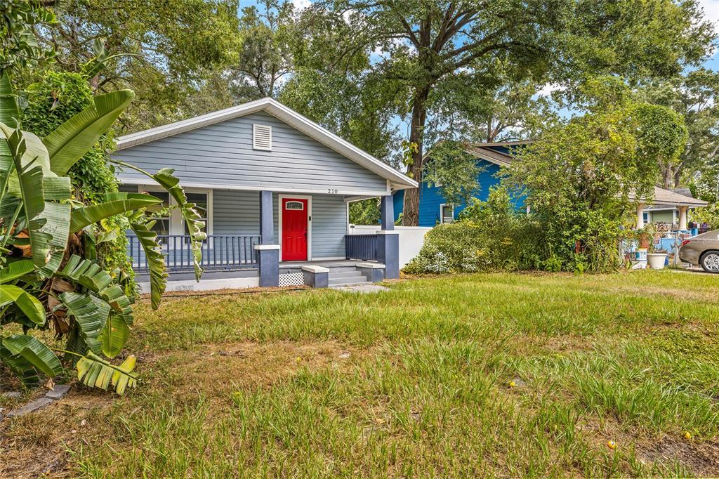 A light blue single-story house features a red front door and a covered front porch — 210 E CLUSTER AVENUE, TAMPA, FL