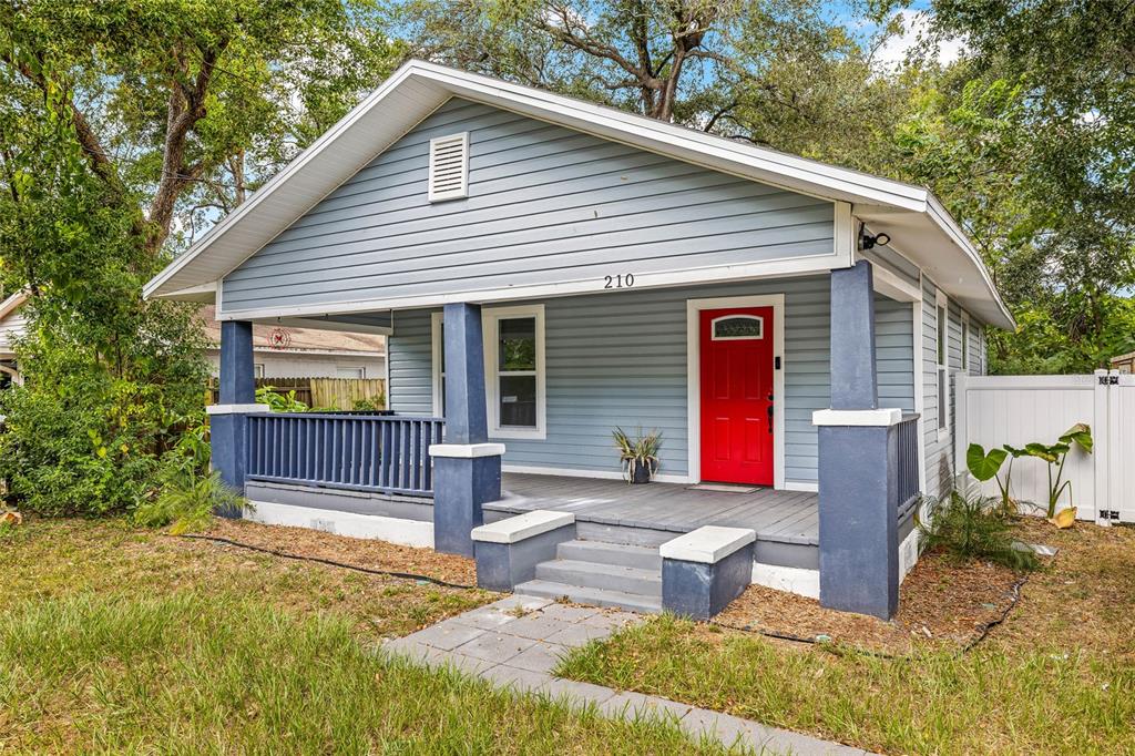 A light blue bungalow with a red front door and a covered front porch — 210 E CLUSTER AVENUE, TAMPA, FL