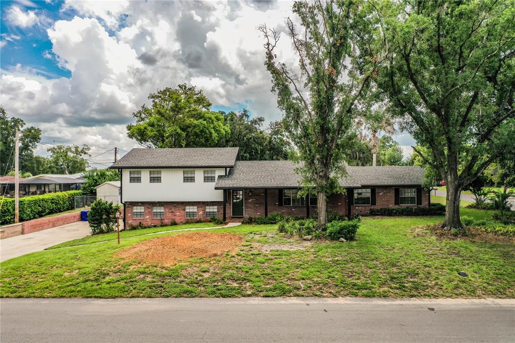 A two-story house with a brick and white siding exterior sits behind a grassy lawn — 4504 MOUNT VIEW DRIVE, LAKELAND, FL