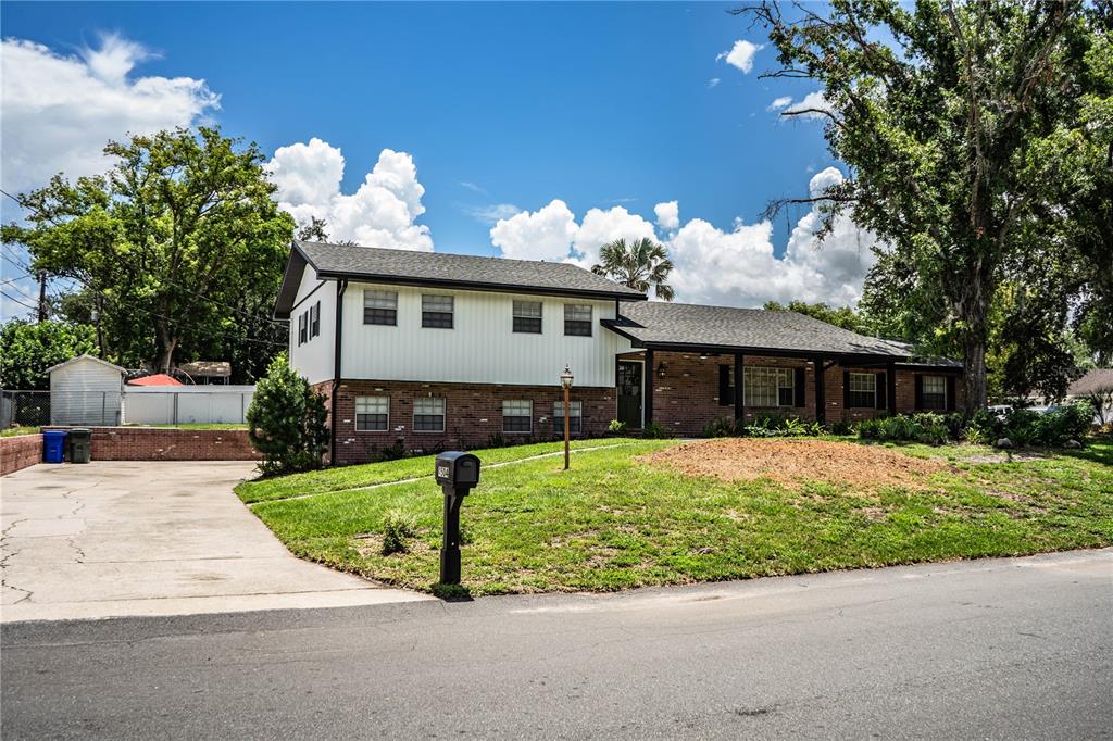 A two-story house with a brick and white siding exterior sits behind a grassy lawn — 4504 MOUNT VIEW DRIVE, LAKELAND, FL