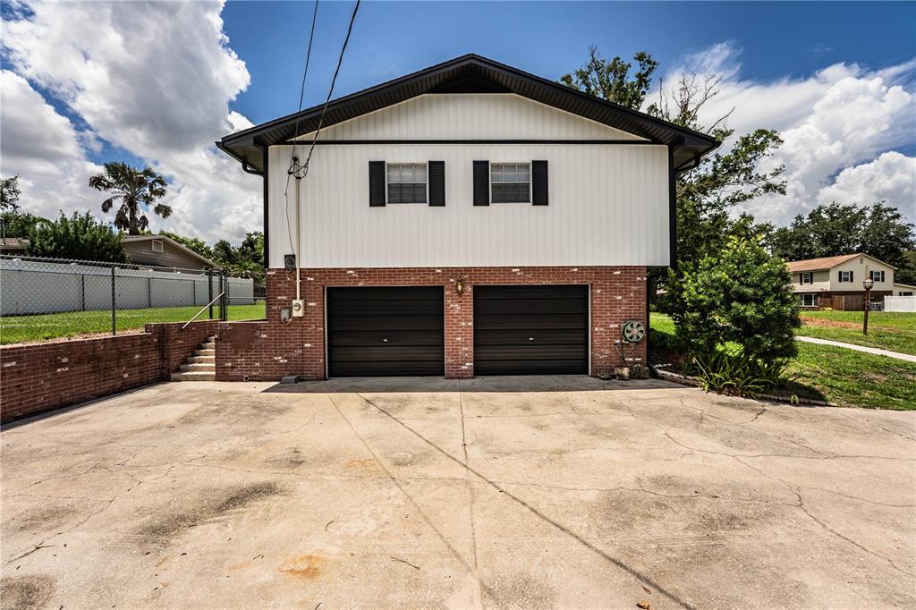 A two-story house exterior features a brick lower level with two garages and white siding above — 4504 MOUNT VIEW DRIVE, LAKELAND, FL