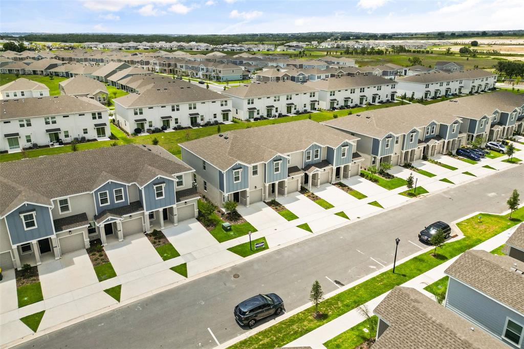 An aerial view shows rows of modern suburban townhouses with driveways and green lawns — 6053 ZEN WAY, CLERMONT, FL