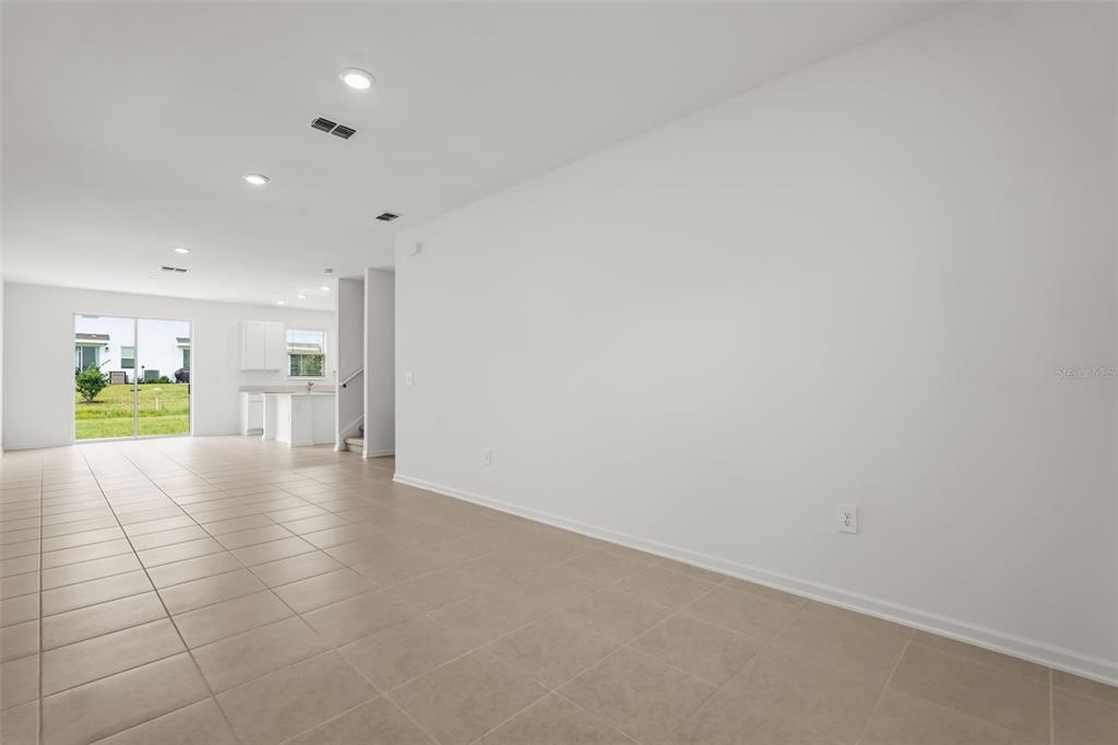 A spacious, open-concept living area features light-colored tile flooring, white walls, and recessed lighting — 6053 ZEN WAY, CLERMONT, FL