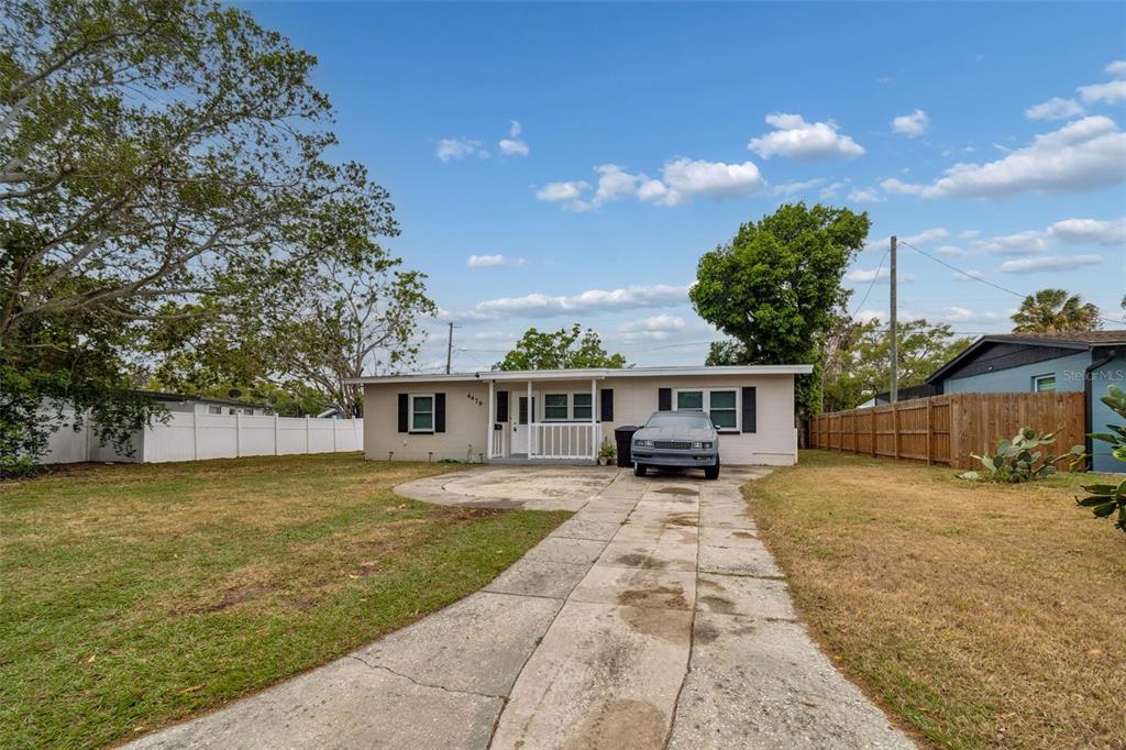 A single-story house with a concrete driveway and a front porch under a blue sky — 4479 PORPOISE DRIVE SE, ST PETERSBURG, FL