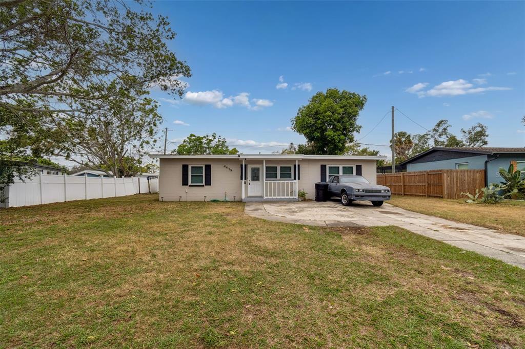 A single-story house with a beige exterior, a front porch, and a concrete driveway — 4479 PORPOISE DRIVE SE, ST PETERSBURG, FL
