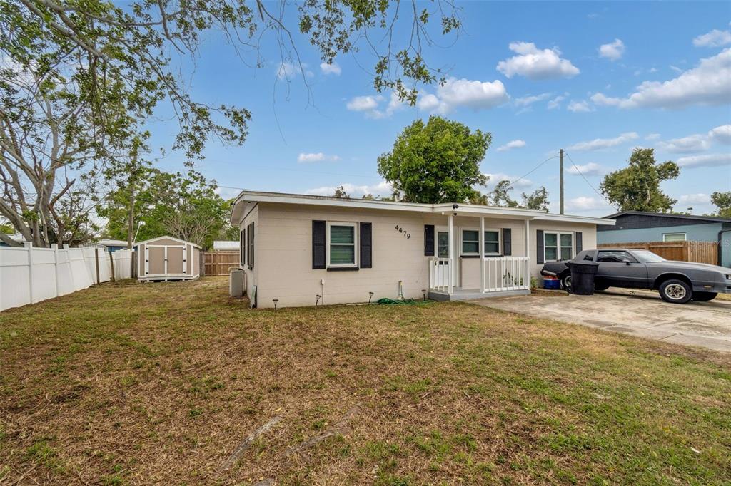 A single-story house with a beige exterior, a small front porch, and a gravel driveway — 4479 PORPOISE DRIVE SE, ST PETERSBURG, FL