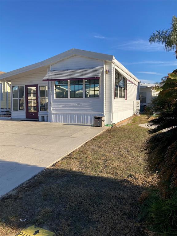 A white manufactured home with a concrete driveway and a metal awning over the windows — 9000 US HIGHWAY 192 UNIT 729, CLERMONT, FL