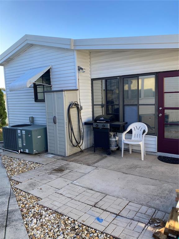 A patio area features a grill, a white chair, a storage shed, and an AC unit — 9000 US HIGHWAY 192 UNIT 729, CLERMONT, FL