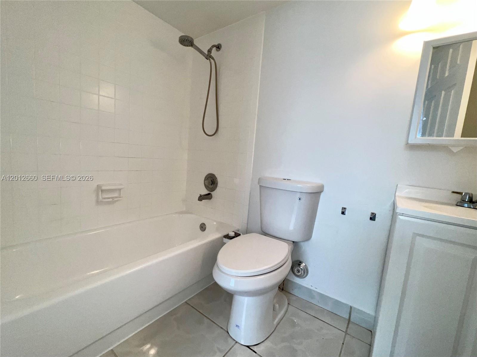 A bathroom features a white bathtub, a toilet, and a vanity with a mirror — 5055 NW 7th St # 303, Miami FL 33126, MIAMI, FL