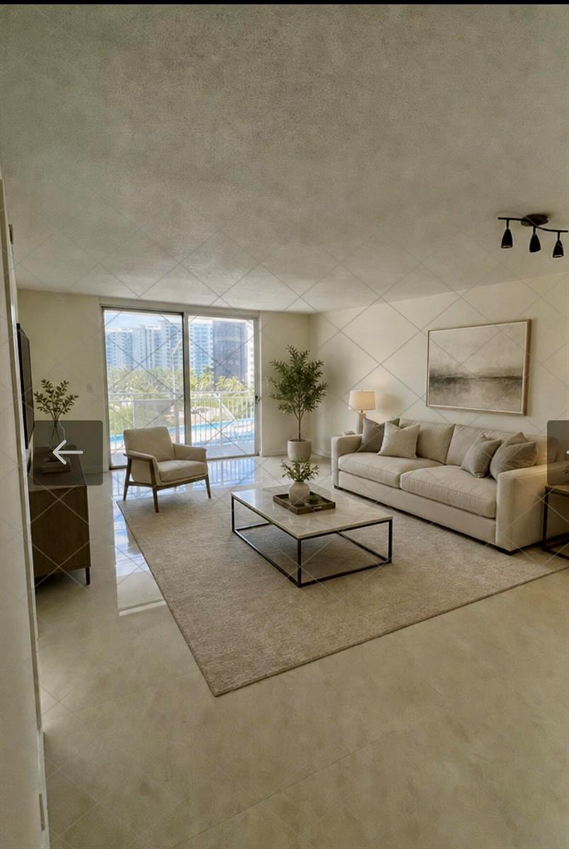 A bright living room features a beige sofa, coffee table, area rug, and balcony access — 1801 S Ocean Drive # 633, Hallandale Beach FL 33009, HALLANDALE BEACH, FL