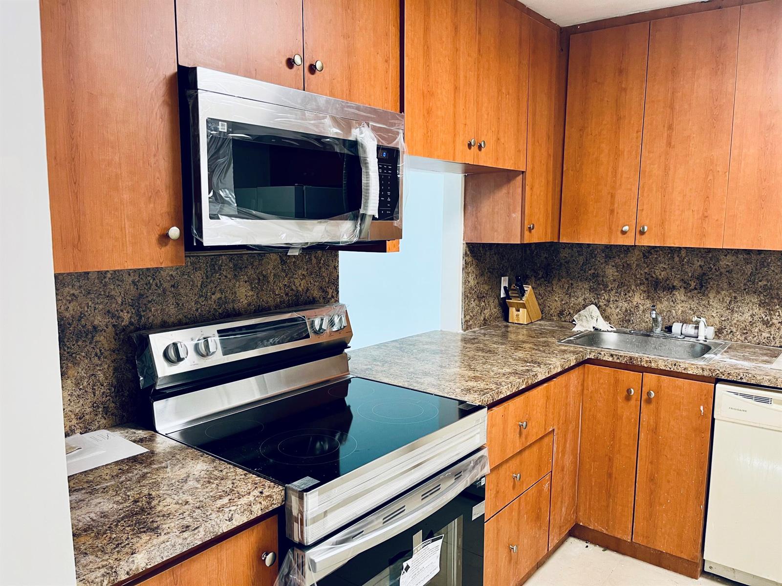 A kitchen features wood cabinets, stainless steel appliances, and a brown speckled laminate countertop — 1801 S Ocean Drive # 633, Hallandale Beach FL 33009, HALLANDALE BEACH, FL