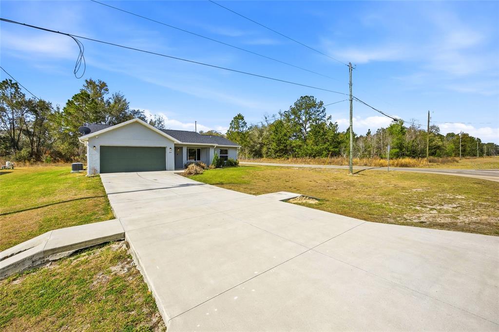 A single-story house with a green garage door and a concrete driveway sits on grass — 224 FISHER ROAD, OCKLAWAHA, FL