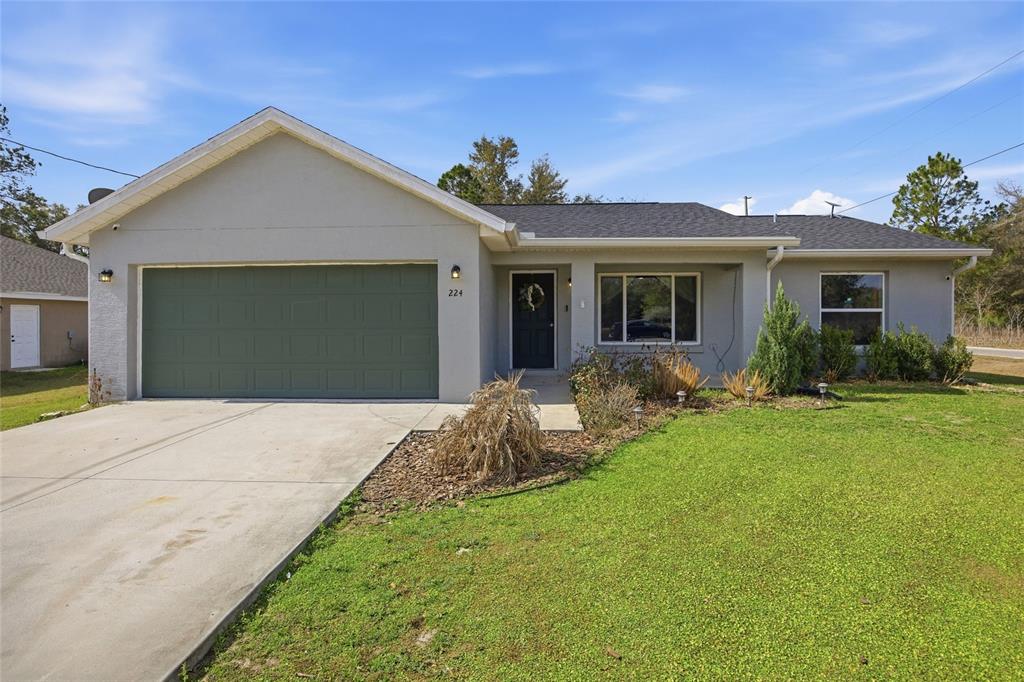 A single-story house with a gray exterior, a two-car garage, and a front lawn — 224 FISHER ROAD, OCKLAWAHA, FL