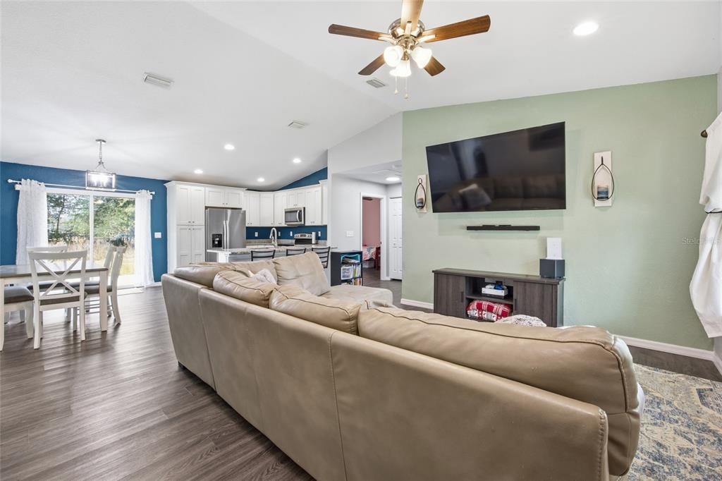 A living room with a tan sectional sofa faces a wall-mounted television and media console — 224 FISHER ROAD, OCKLAWAHA, FL