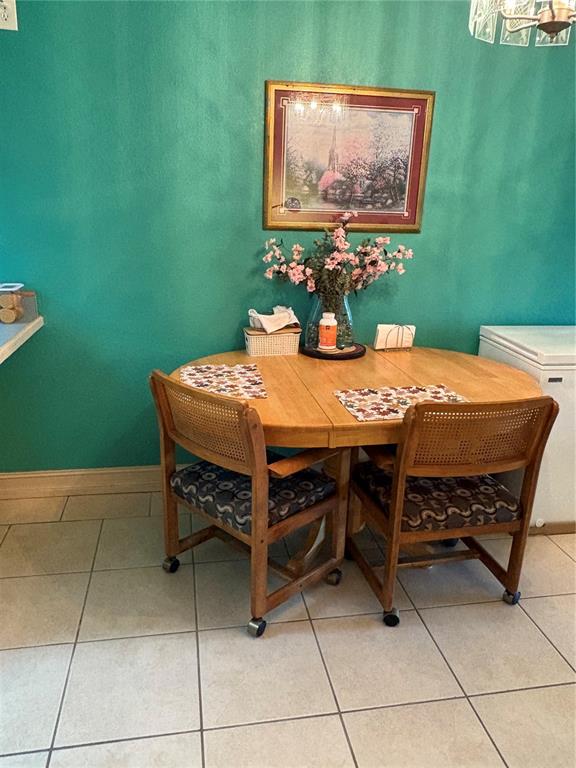 A dining area features a round wooden table with two cane-back chairs on tile flooring — 1200 37TH STREET N UNIT 107, ST PETERSBURG, FL