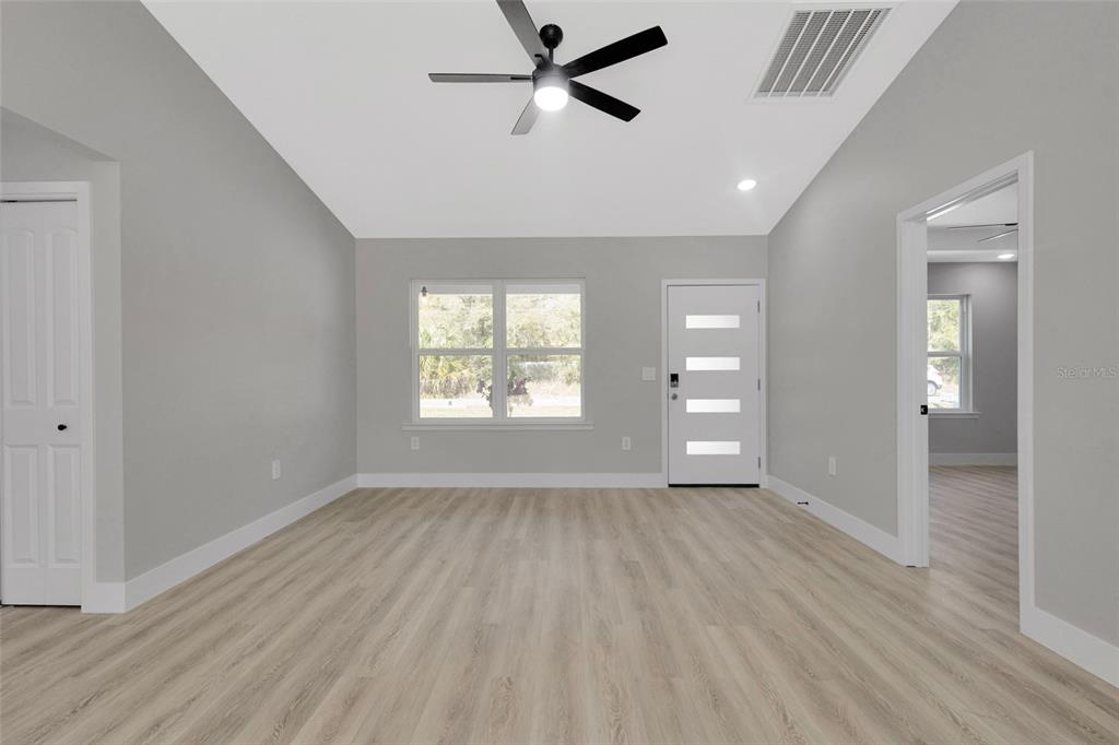 A single-story house with gray horizontal siding, a white garage door, and a covered porch — 6938 SE 122ND LANE, BELLEVIEW, FL
