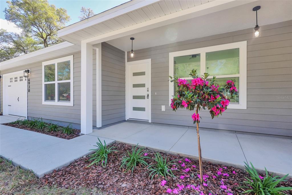 A room with light wood-look flooring, a modern chandelier, and a wall-mounted electric fireplace — 6938 SE 122ND LANE, BELLEVIEW, FL