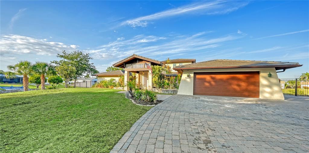 A single-story house with a large garage, stone accents, and a paved driveway — 5500 MERRIMAC DRIVE, SARASOTA, FL