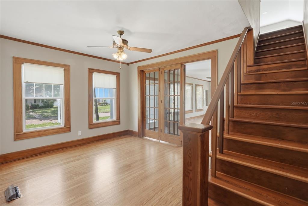 A room with hardwood floors, a wooden staircase, and French doors leading to another space — 4227 2ND AVENUE N, ST PETERSBURG, FL