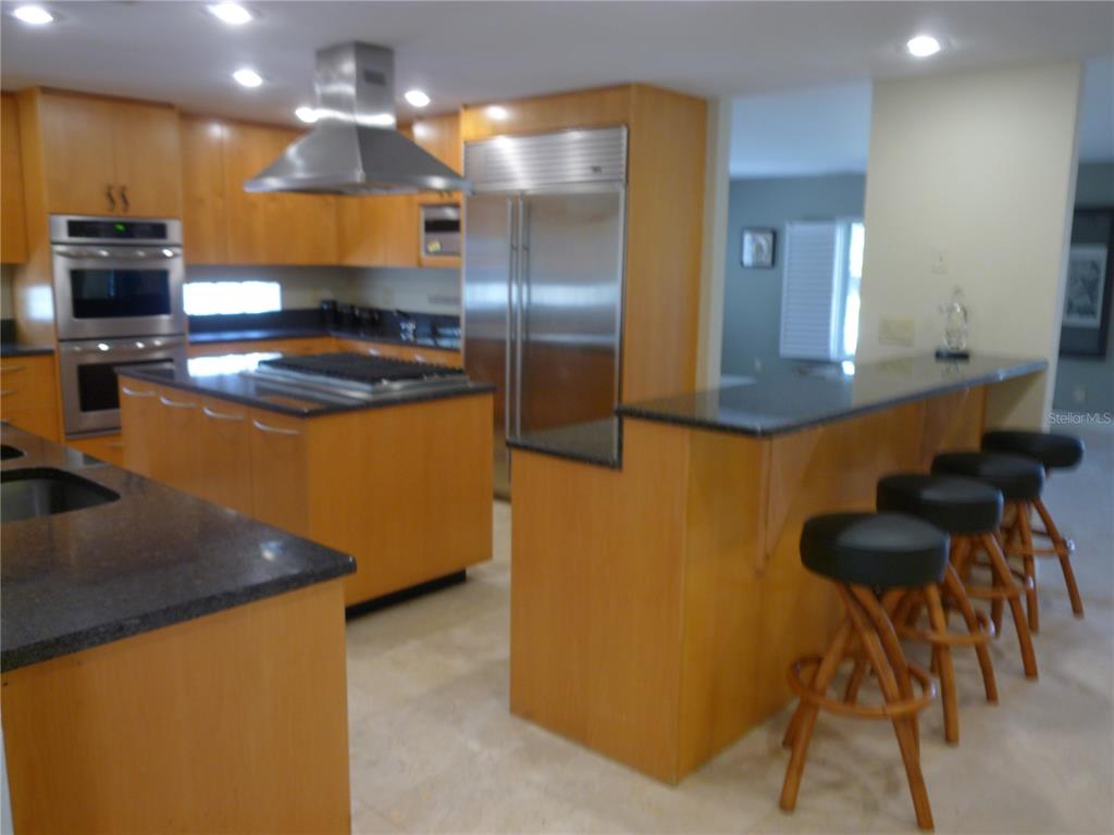 A kitchen features light wood cabinetry, stainless steel appliances, and a black granite breakfast bar — 300 BRIGHTWATERS BOULEVARD NE, ST PETERSBURG, FL