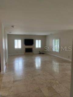A spacious living room features light-colored tile flooring, a fireplace, and a wall-mounted television — 300 BRIGHTWATERS BOULEVARD NE, ST PETERSBURG, FL