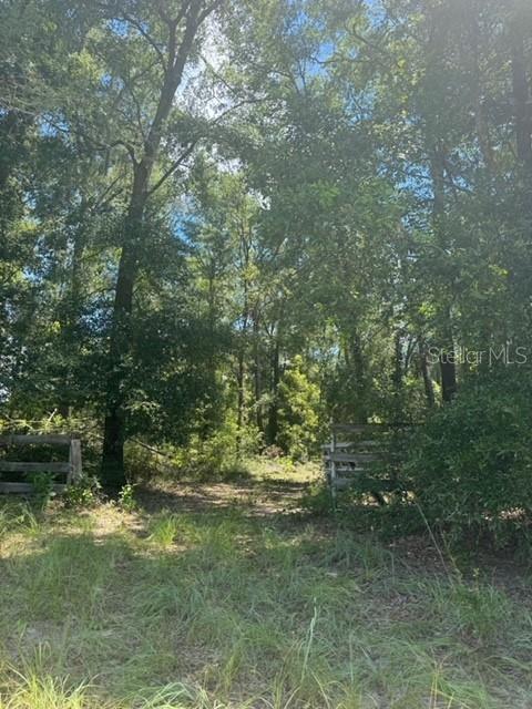 A dirt path leads into a wooded area between two wooden fence sections — SW COLES COURT, FORT WHITE, FL