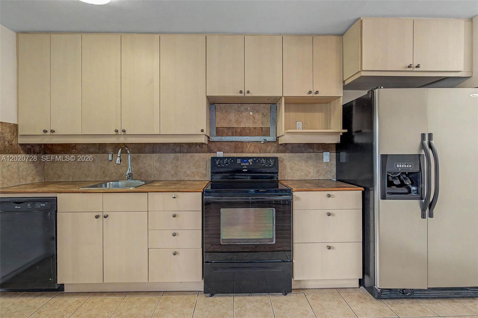 A kitchen features light wood cabinets, a black stove, a black dishwasher, and a refrigerator — 60 NW 79th St # 6, Miami FL 33150, MIAMI, FL