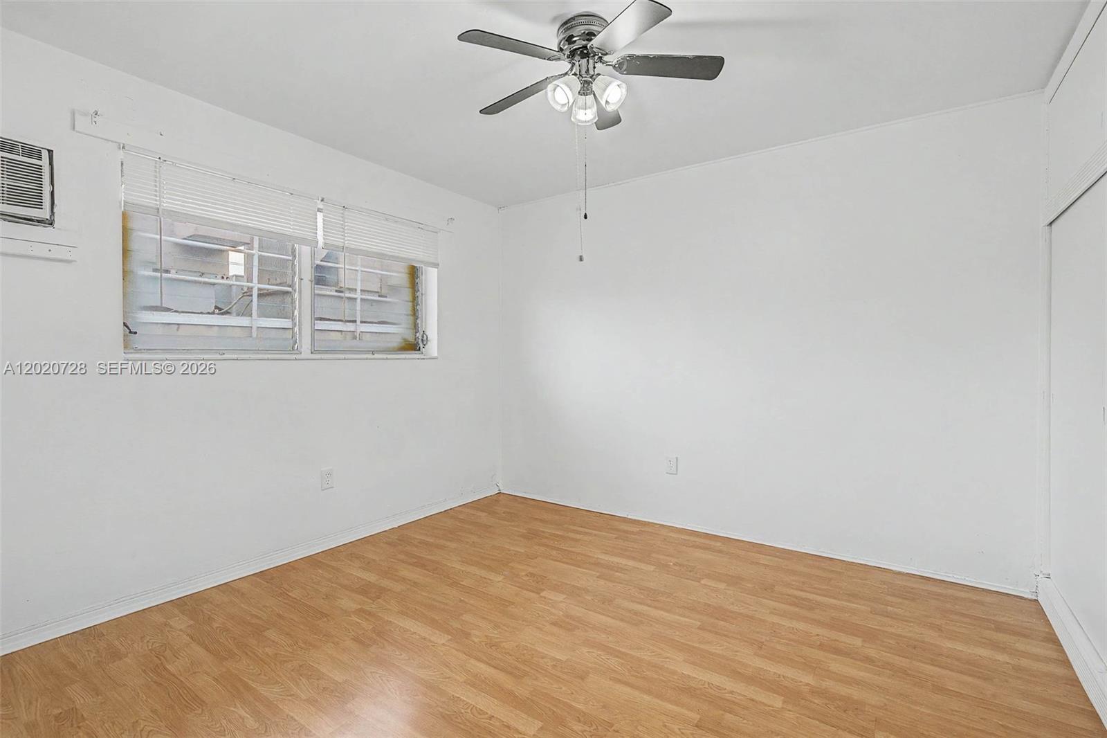 An empty bedroom features white walls, light wood-look flooring, a ceiling fan, and windows — 60 NW 79th St # 6, Miami FL 33150, MIAMI, FL