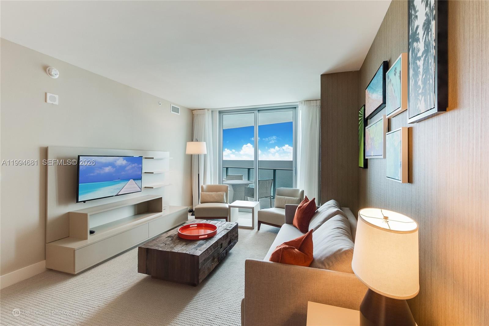 A living room features a television, a wooden coffee table, and a balcony with ocean views — 4111 S Ocean Dr # 2707, Hollywood FL 33019, HOLLYWOOD, FL