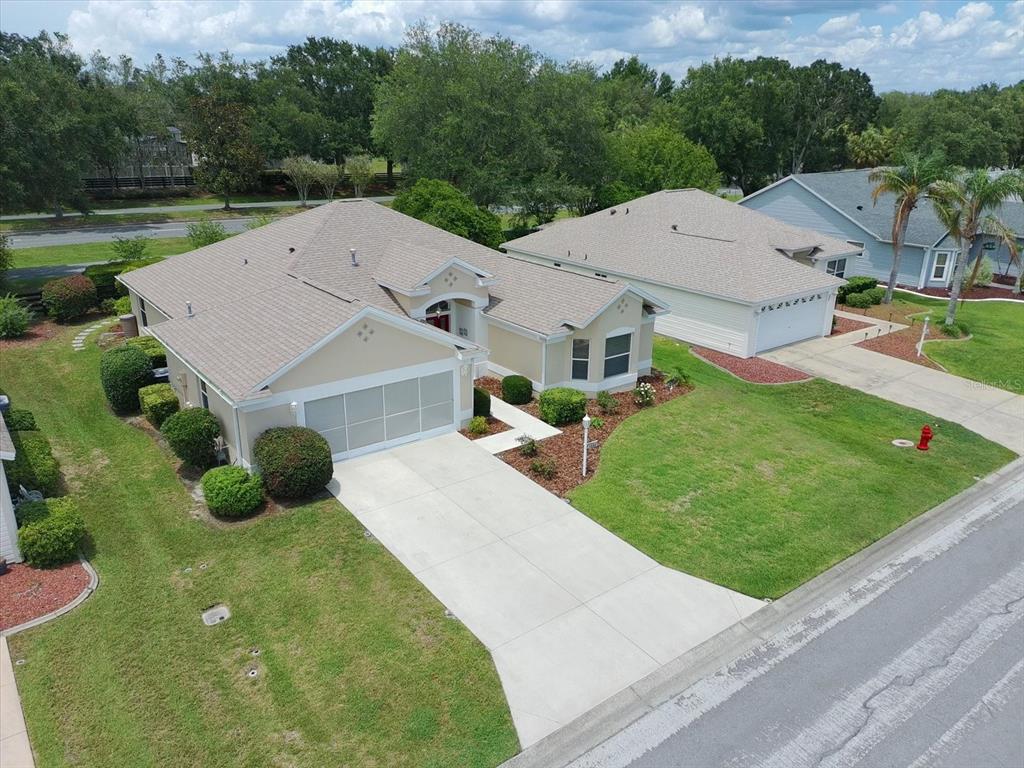 An aerial view shows a tan single-story house with a two-car garage and driveway — 1332 CAMERO DRIVE, THE VILLAGES, FL