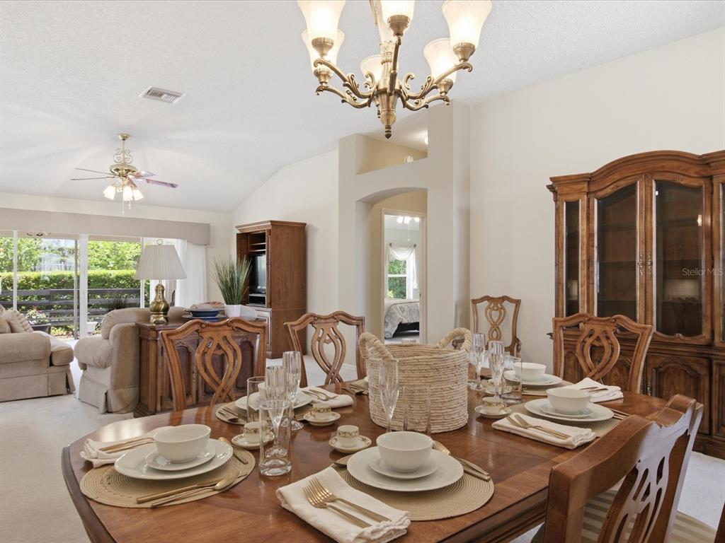 A dining room with a wooden table set for dinner, a chandelier, and a hutch — 1332 CAMERO DRIVE, THE VILLAGES, FL