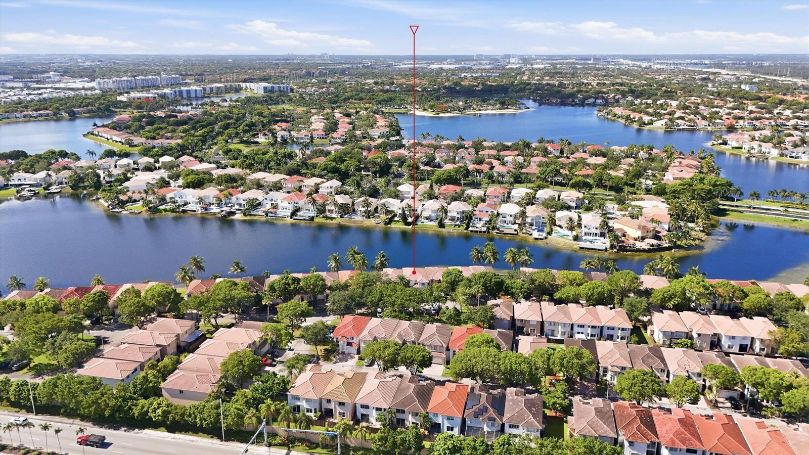 An aerial view shows a residential neighborhood with houses situated along a large lake — 11180 NW 73rd Street, Doral FL 33178, DORAL, FL