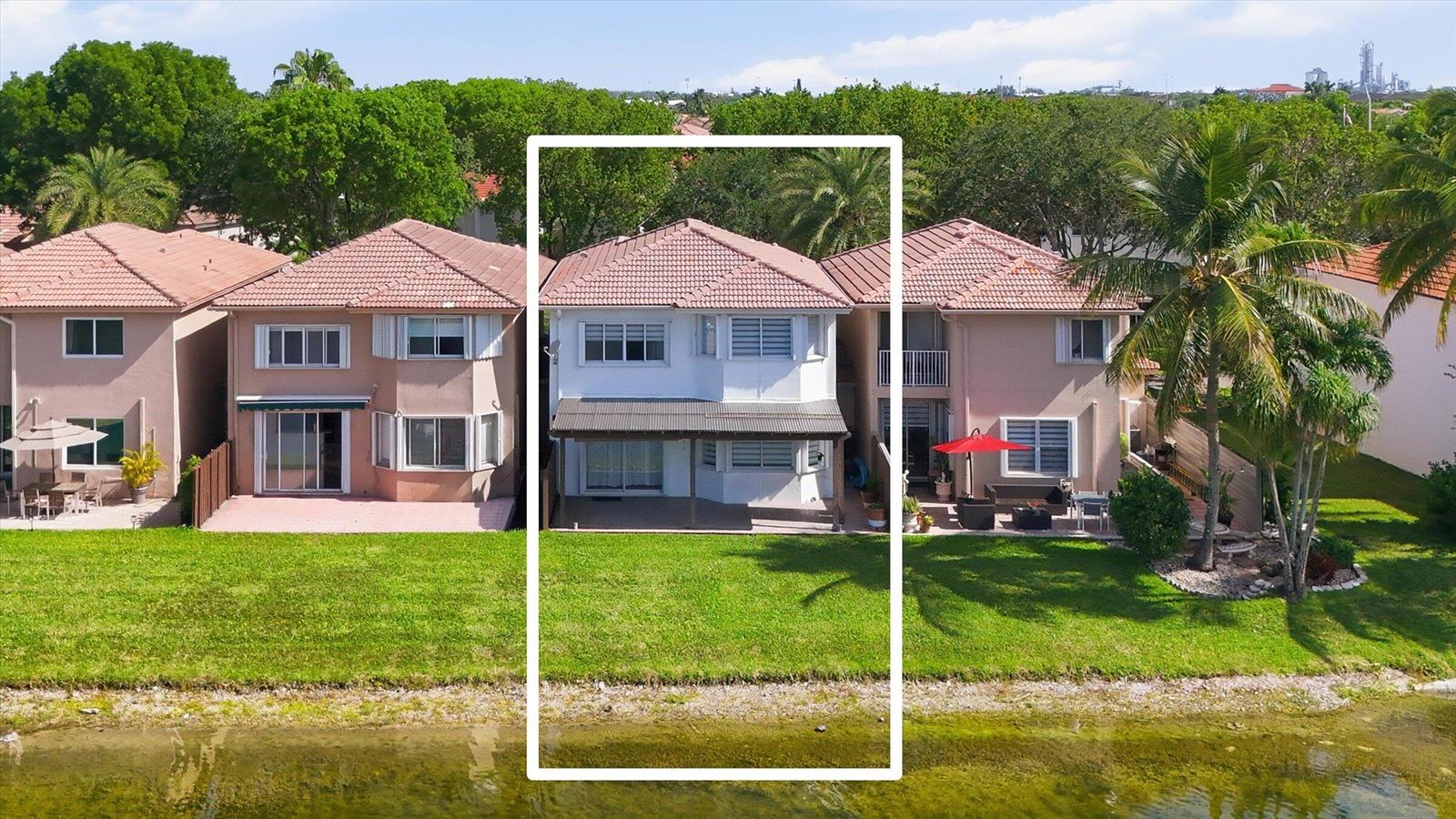 An aerial view of a white two-story house with a patio overlooking a lake — 11180 NW 73rd Street, Doral FL 33178, DORAL, FL