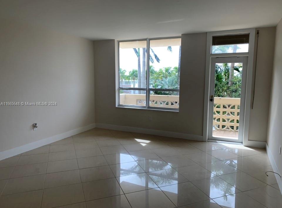 A bright room with beige tile flooring, a large window, and a glass-paned balcony door — 10185 Collins Ave # 406, Bal Harbour FL 33154, BAL HARBOUR, FL