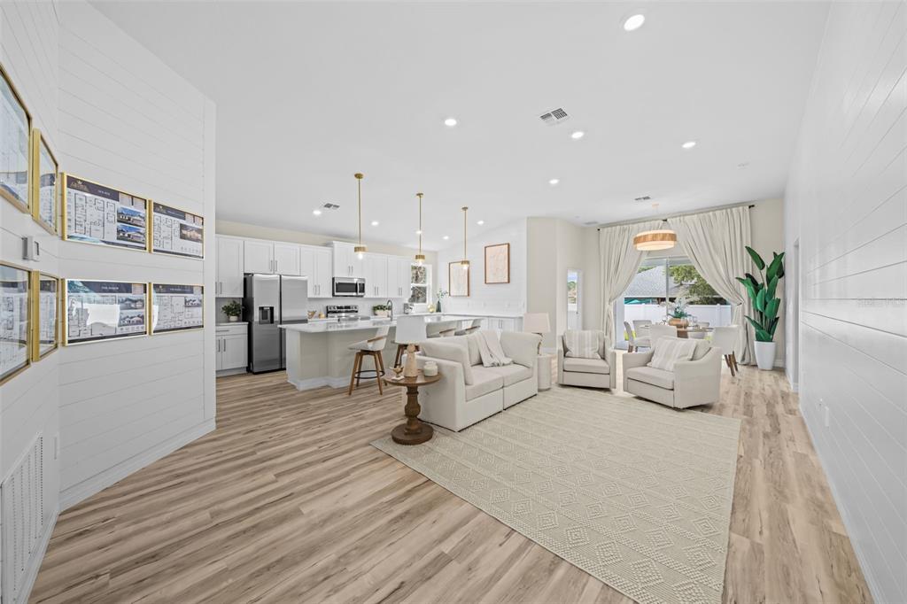 An open-concept living room and kitchen featuring white cabinetry, light wood floors, and neutral furniture — 3121 LA FRANCE AVENUE SW, PALM BAY, FL