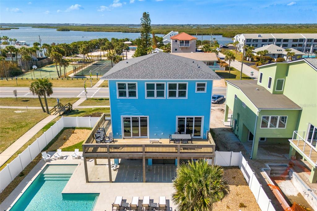 An aerial view shows a blue house with a deck, pool, and nearby tennis courts — 6635 TURTLEMOUND ROAD, NEW SMYRNA BEACH, FL