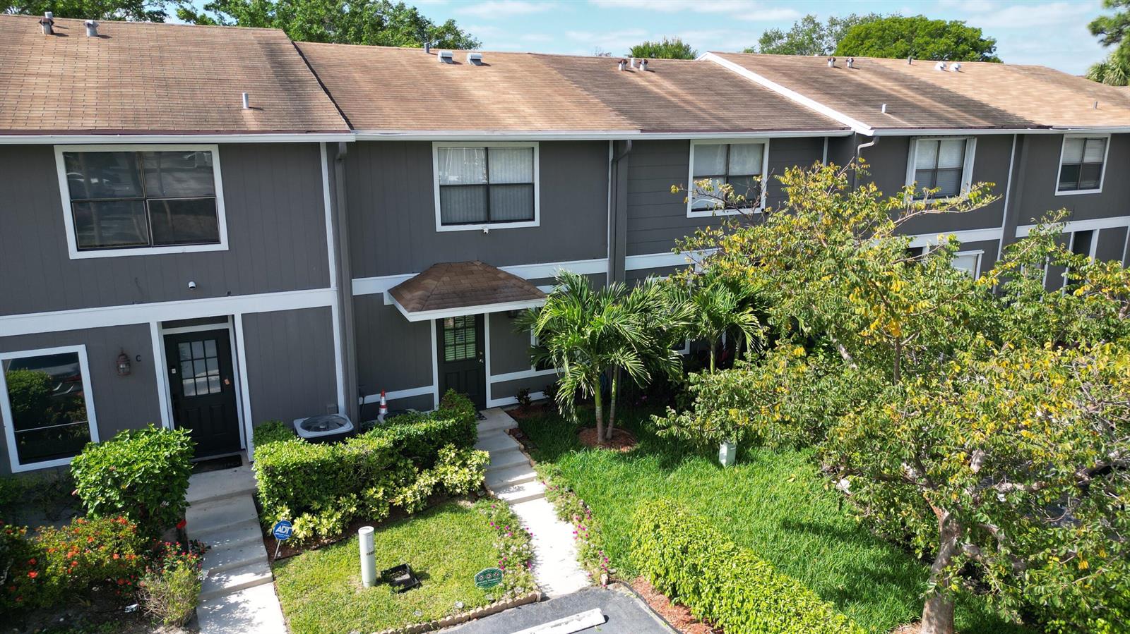 An exterior view of a two-story gray townhouse with a front walkway and landscaping — 850 Hill Drive # D, West Palm Beach FL 33415, WEST PALM BEACH, FL
