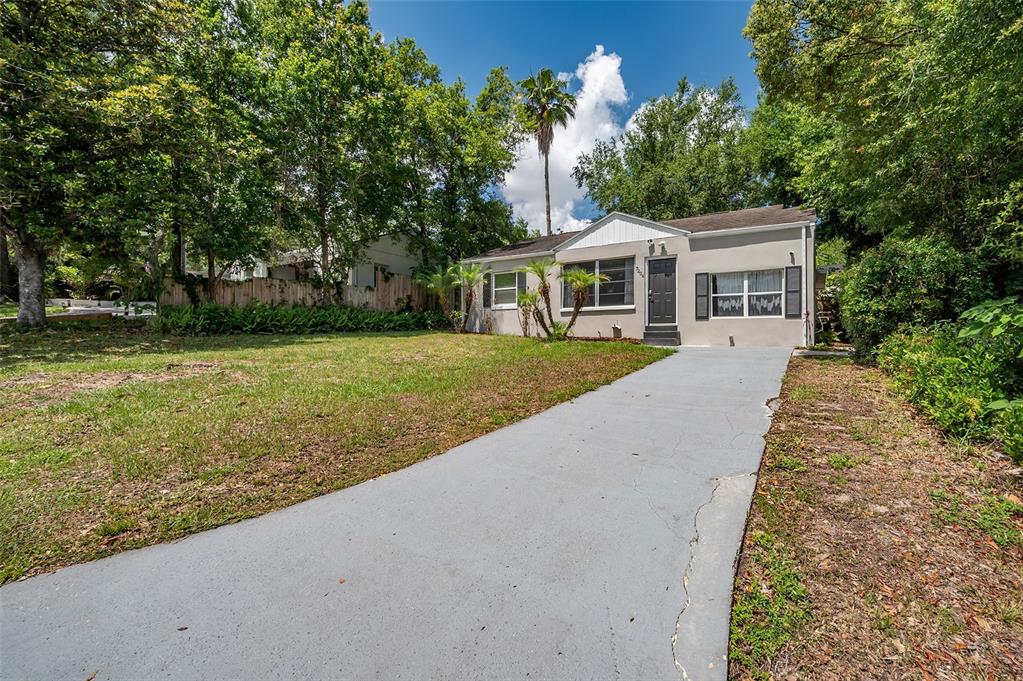 A single-story house with a gray exterior, a concrete driveway, and a large front yard — 7204 N 15TH STREET, TAMPA, FL