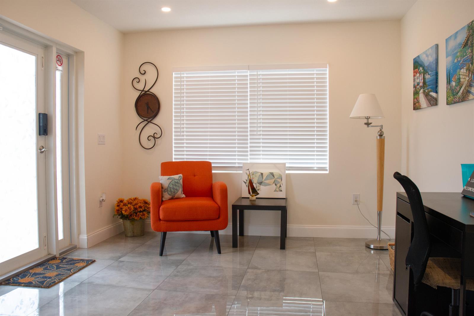 A bright room features an orange armchair, a small side table, and a floor lamp — 158 E 23rd Street, West Palm Beach FL 33404, WEST PALM BEACH, FL