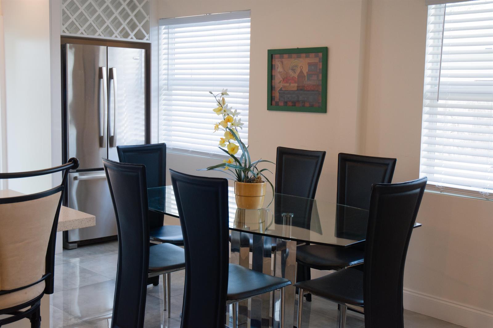 A dining area features a glass table with six black chairs and a yellow planter — 158 E 23rd Street, West Palm Beach FL 33404, WEST PALM BEACH, FL