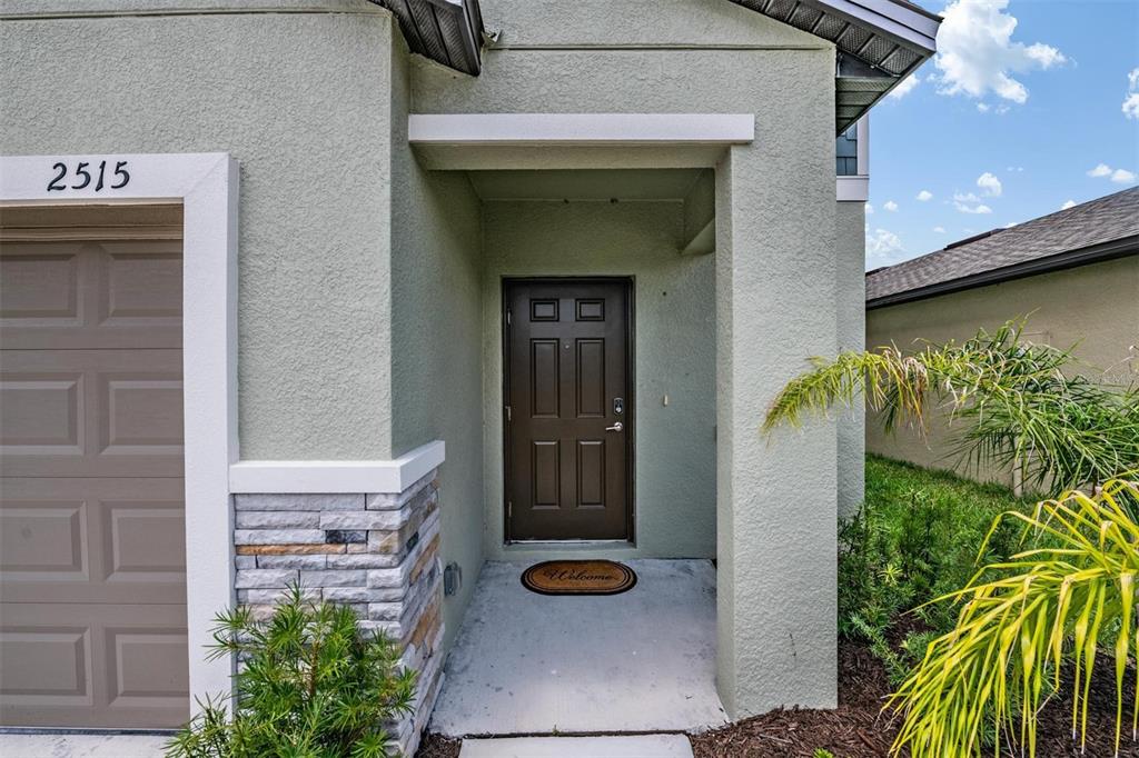 The exterior of a house features a brown front door, stone accents, and a garage — 2515 VICTORIOUS FALLS AVENUE, PLANT CITY, FL