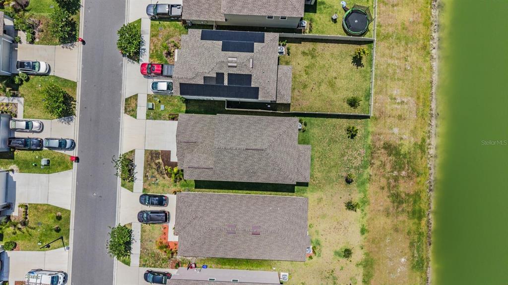 An aerial view shows a row of suburban houses with driveways and backyards bordering water — 2515 VICTORIOUS FALLS AVENUE, PLANT CITY, FL