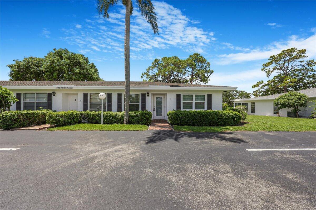 A single-story white building with dark shutters and a palm tree in the front yard — 5178 Privet Place # D, Delray Beach FL 33484, DELRAY BEACH, FL