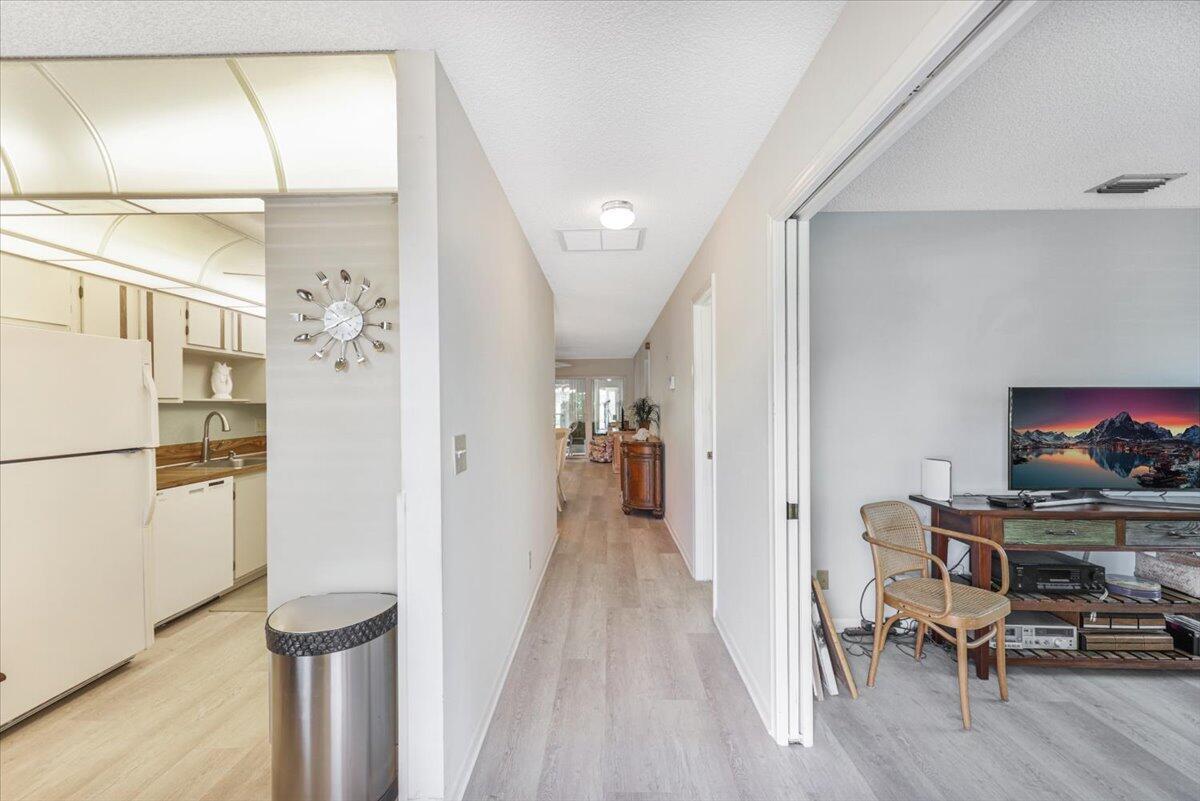 A hallway connects a kitchen on the left to a room with a television on the right — 5178 Privet Place # D, Delray Beach FL 33484, DELRAY BEACH, FL