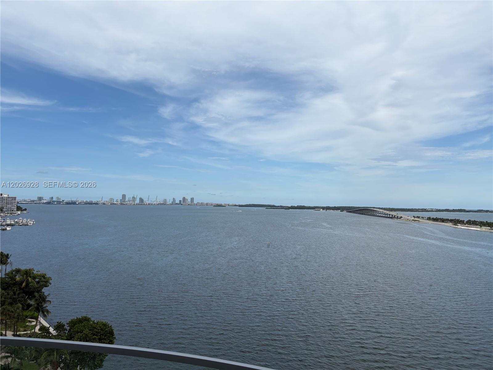 An elevated view of a bay with a bridge, distant city skyline, and lush vegetation — 175 SE 25 Road # 901, Miami FL 33129, MIAMI, FL