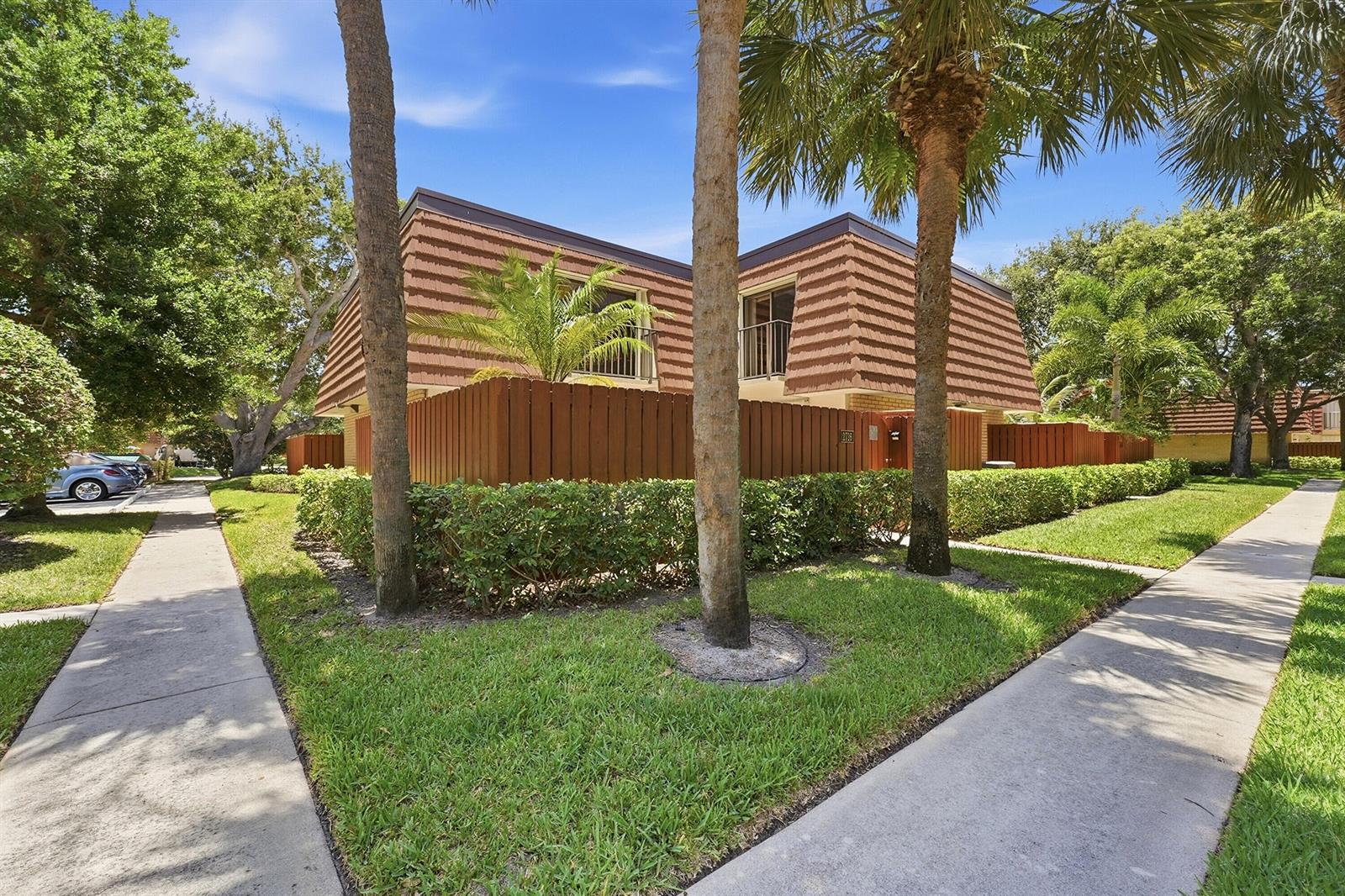 A two-story building with a brown mansard roof, wooden privacy fence, and surrounding palm trees — 2716 27th Court, Jupiter FL 33477, JUPITER, FL