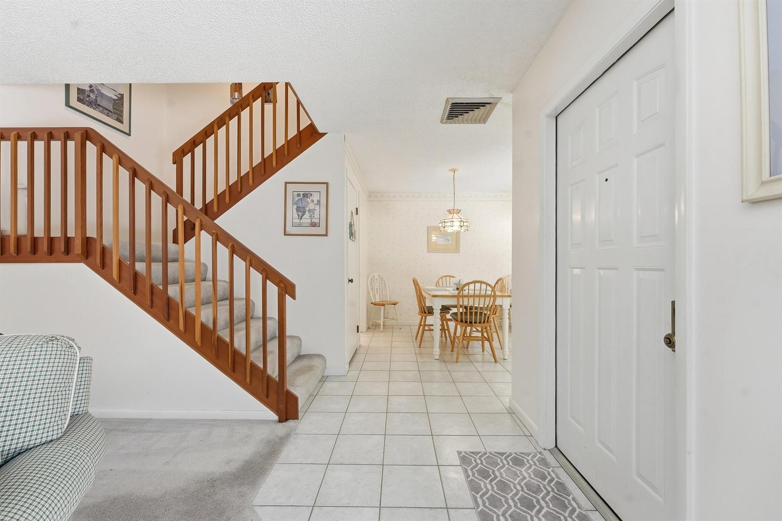 An entryway with tiled floors leads to a dining area and a wooden staircase — 2716 27th Court, Jupiter FL 33477, JUPITER, FL