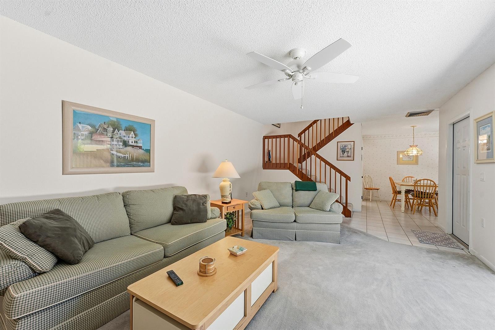 A living room with a plaid sofa, loveseat, wooden coffee table, and a staircase — 2716 27th Court, Jupiter FL 33477, JUPITER, FL
