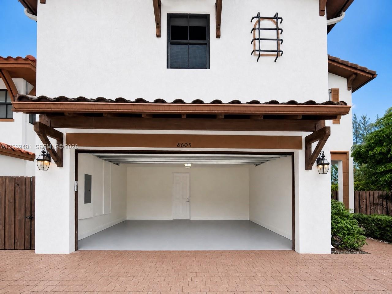 A two-car garage with a gray epoxy floor and a white door is shown — 8605 NW 102nd Ct, Doral FL 33178, DORAL, FL